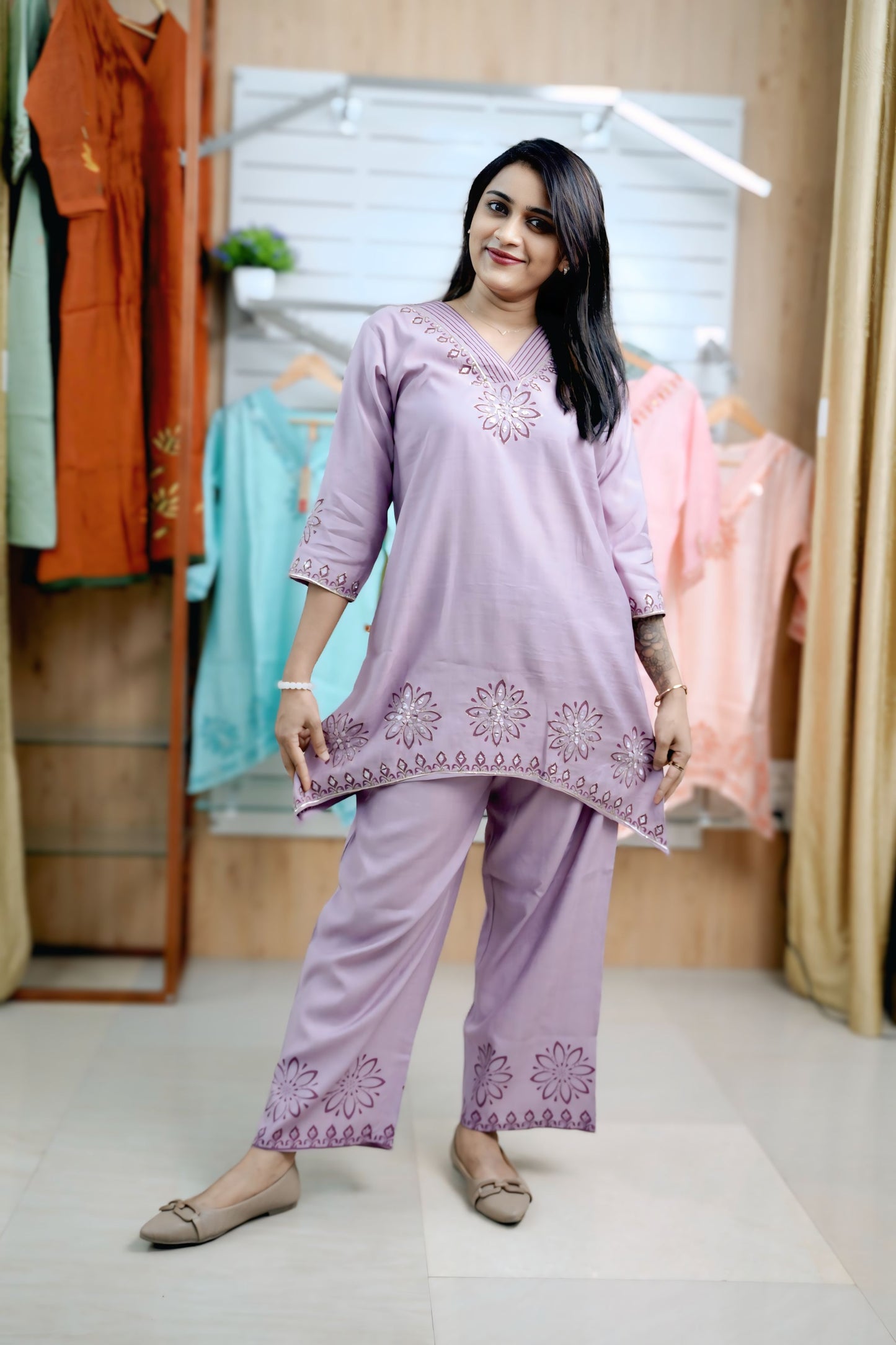 Woman wearing a lavender embroidered outfit in a clothing store.Stylish ladies coord set with V-neck and thread detailing