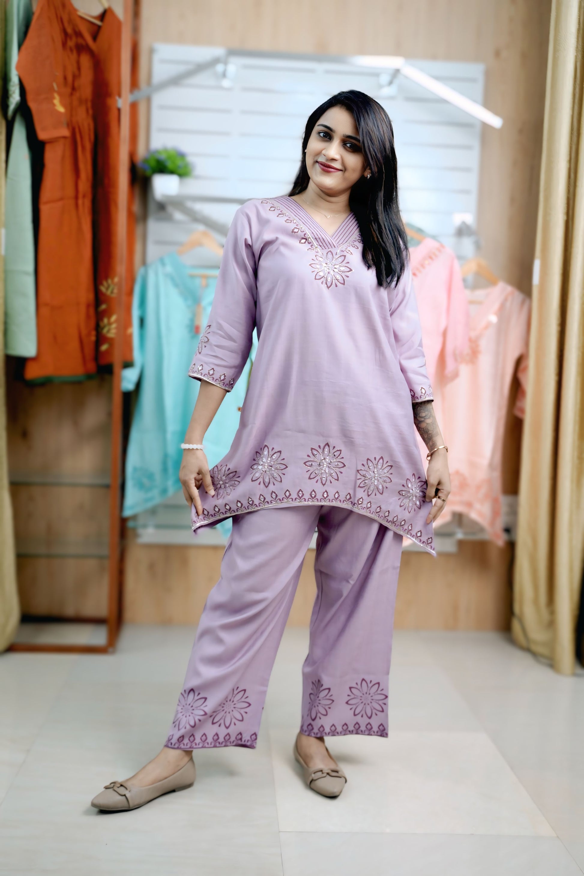 Woman wearing a lavender embroidered outfit in a clothing store.Stylish ladies coord set with V-neck and thread detailing